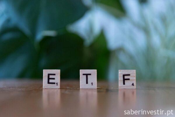 Scrabble tiles spelling ETF on a wooden surface with blurred green background.